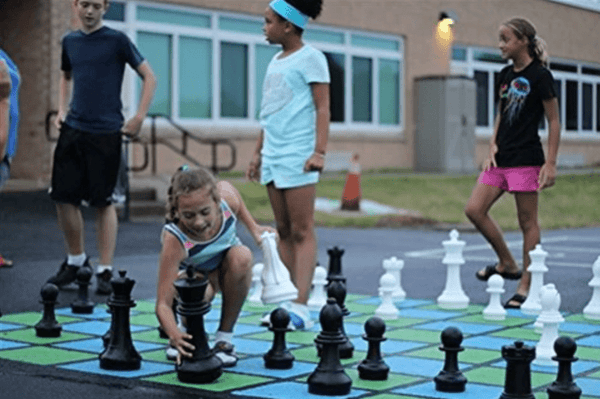 Kids playing with the MegaChess 16 Inch Giant Plastic Chess Set on a Painted Chessboard