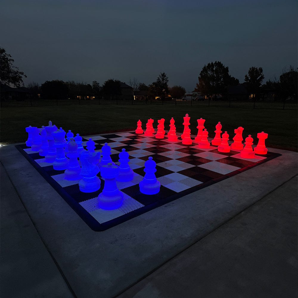 Two Foot Tall LED Giant Chess Sets lit in blue and red at night on a large outdoor chessboard.