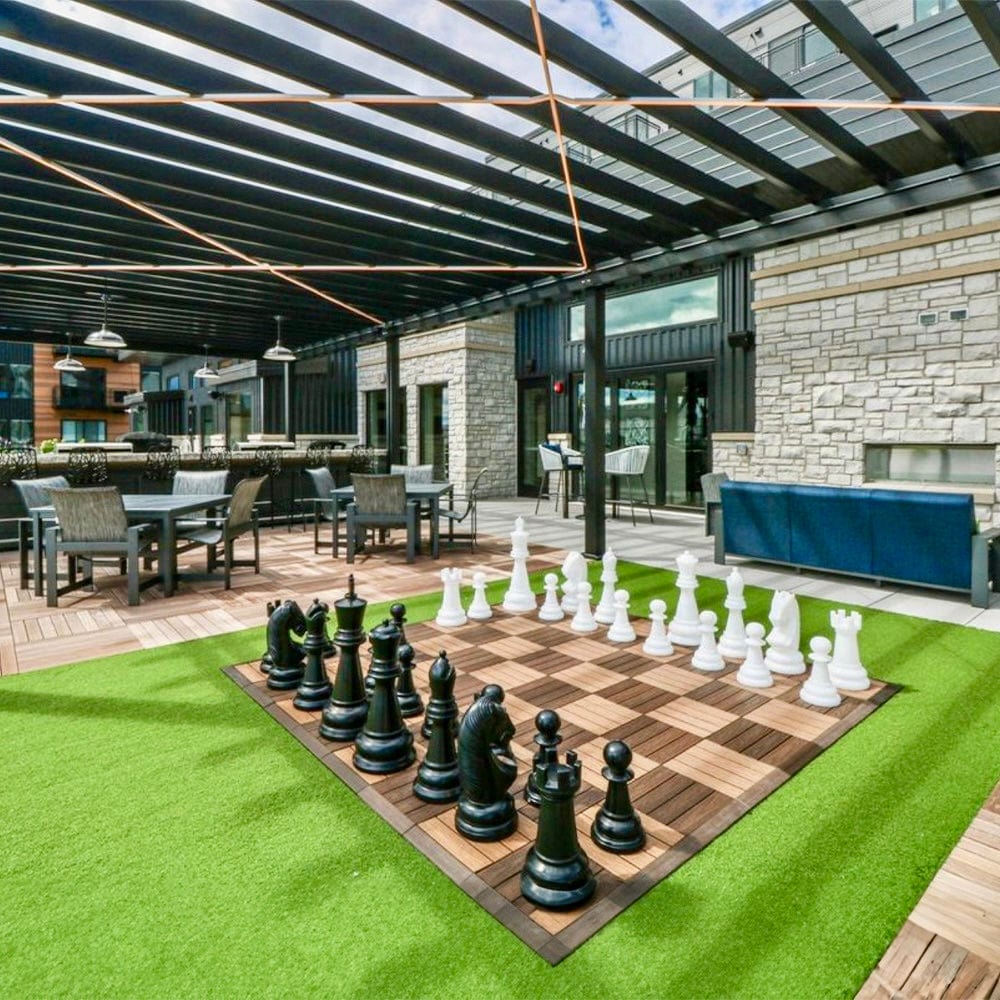 Two Foot Tall Perfect Giant Chess Sets displayed on a vibrant outdoor chessboard in a stylish setting.