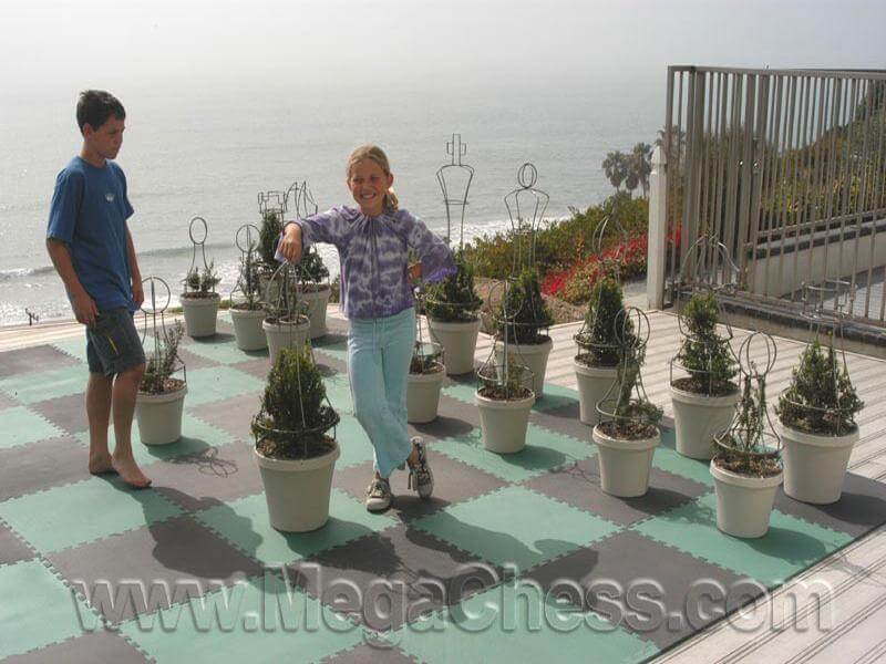 Children playing with Three Foot Tall Wire Frame/Topiary Giant Chess Sets on an outdoor chessboard.