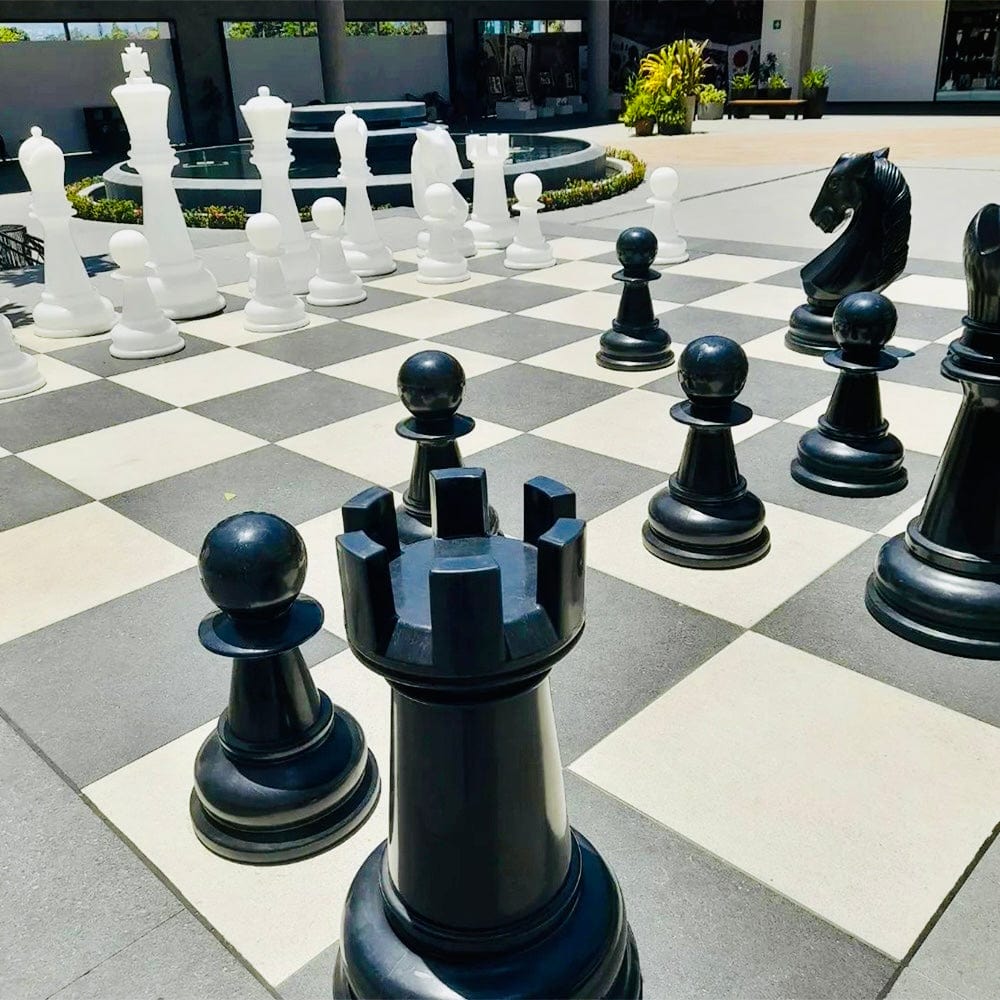 Four Foot Tall Perfect Giant Chess Sets displayed on an outdoor chessboard with large black and white pieces.