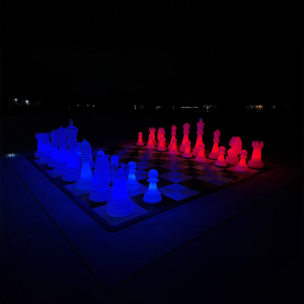 Three Foot Tall LED Giant Chess Sets illuminated at night with blue and red glowing pieces on a checkered board.